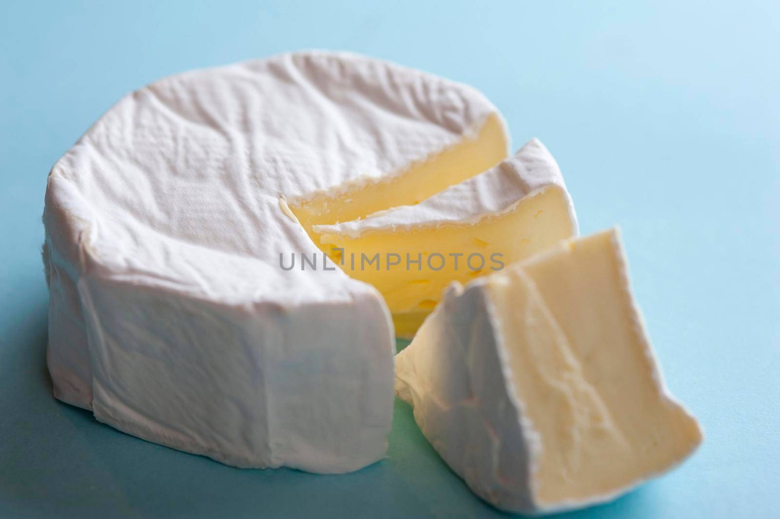 Round soft brie cheese with a wedge removed, closeup high angle view
