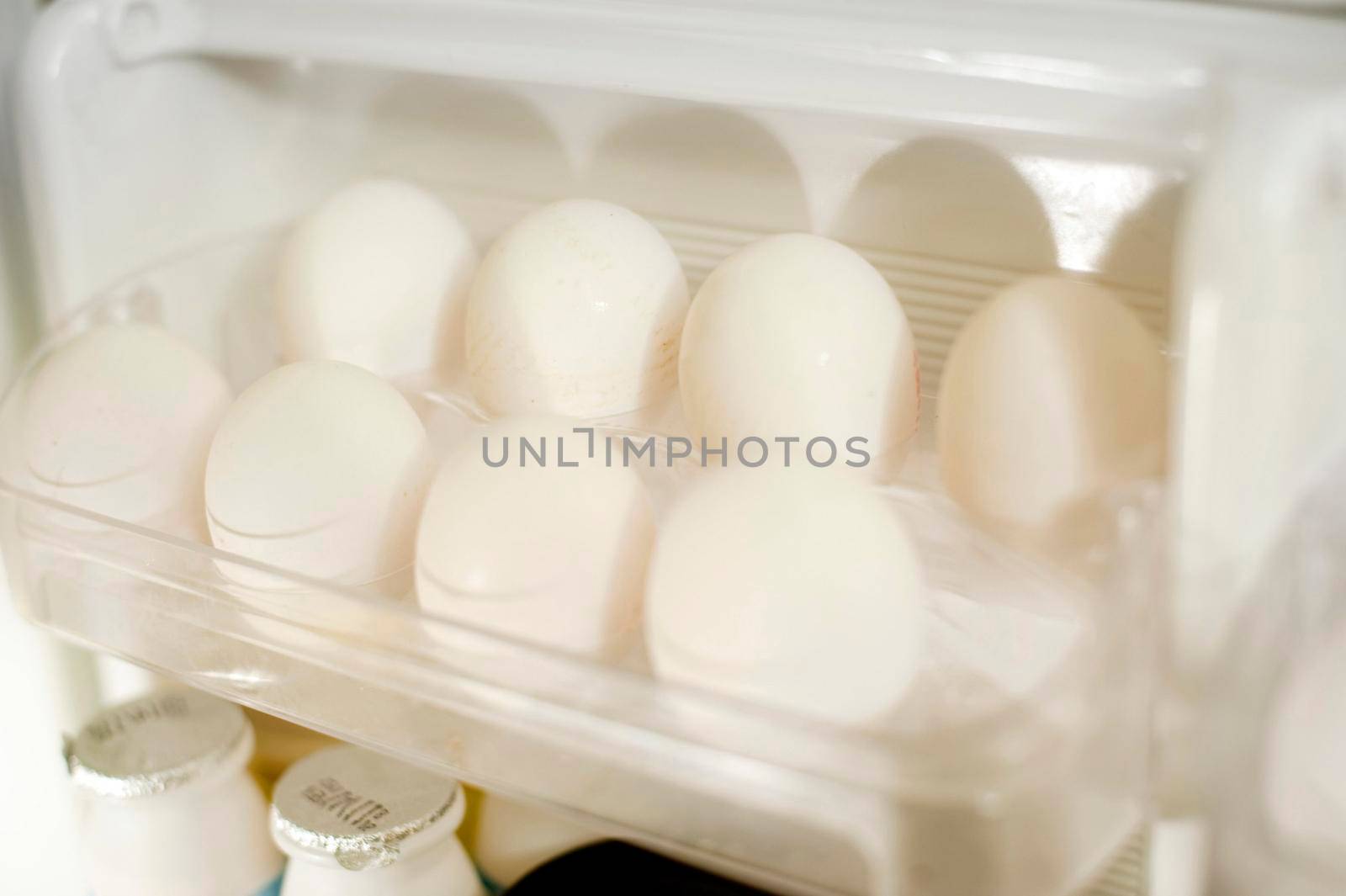 Tray of farm fresh white eggs in the the door of a fridge to be used as a healthy source of protein in cooking