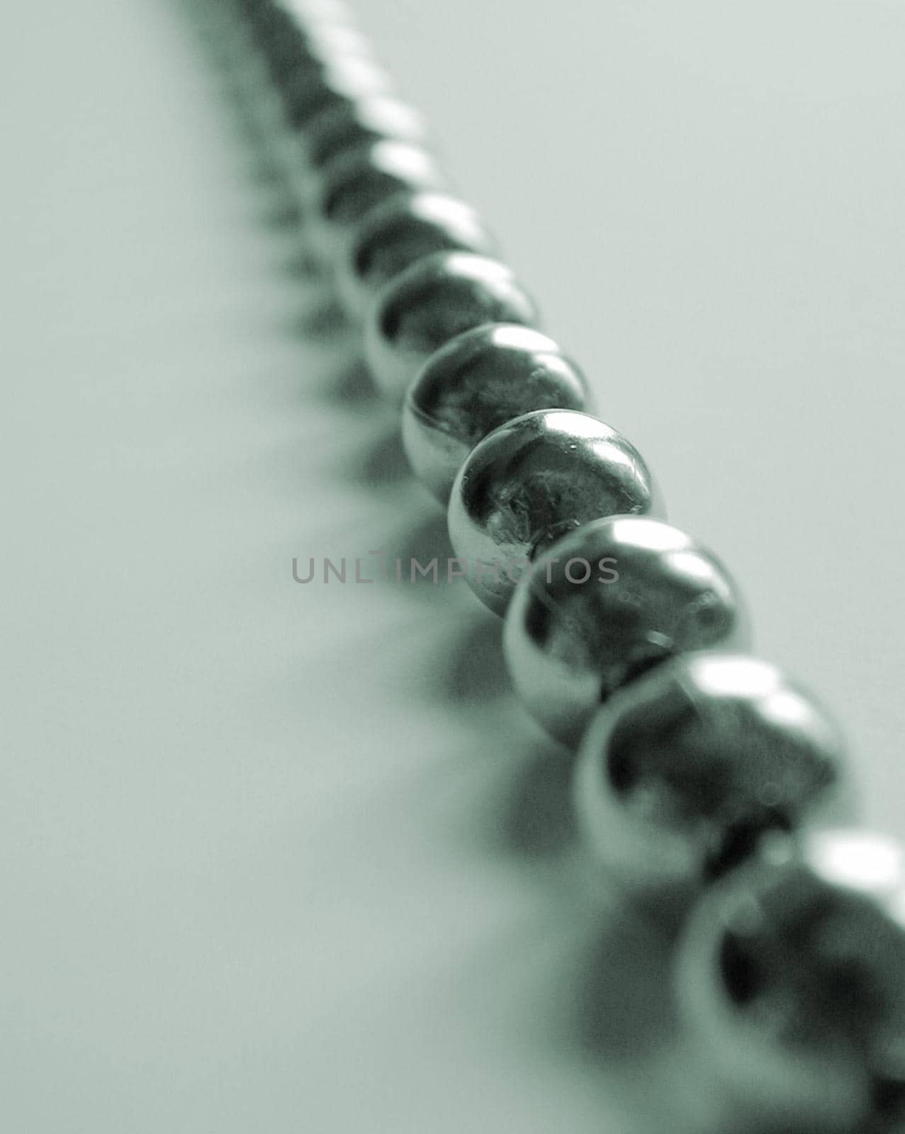 Unusual background with close up view of metal balls strung together against a light colored table
