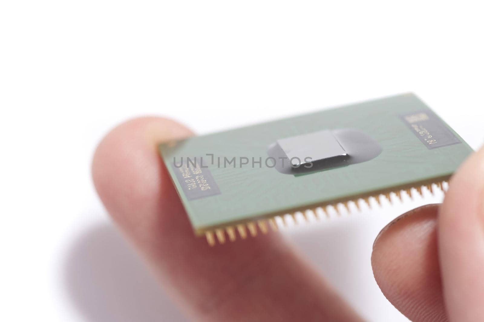 Close-up image of man holding CPU chip in fingers against white background