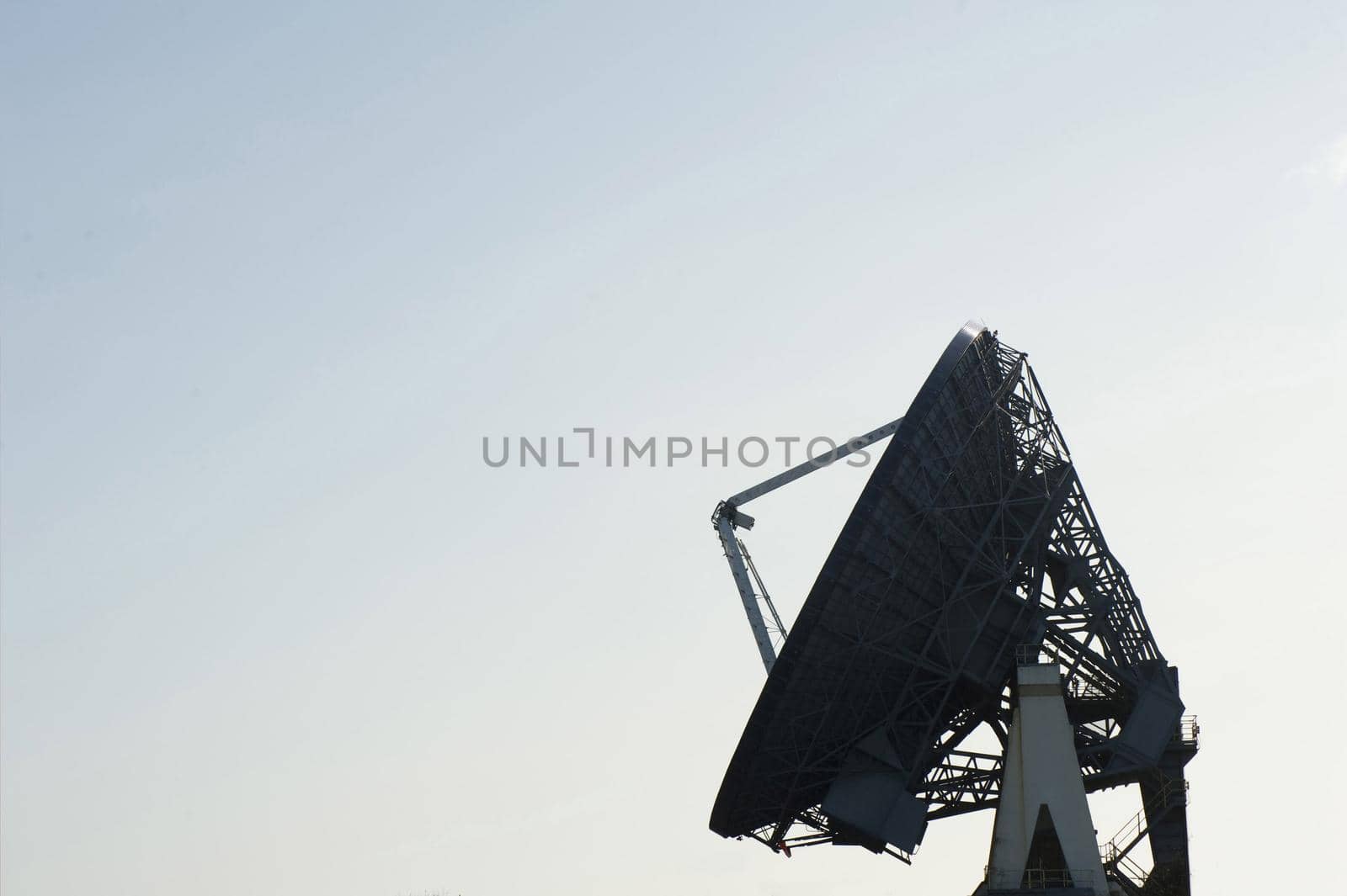 Silhouette of a parabolic ground satellite dish antenna against a clear blue sky with copy space in a concept of telecommunication