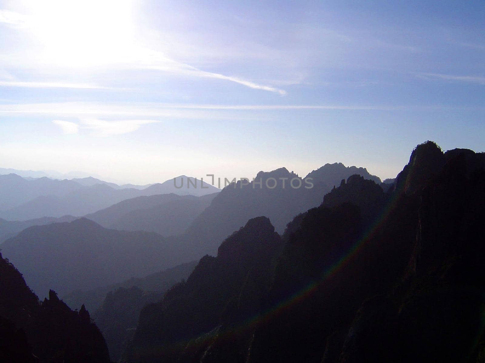 Beautiful Scenic Overview of Huangshan Mountain Range in Eastern China with Blue Sky and Bright Sunshine, Mountains Leading into the Hazy Distance Under Bright Sun