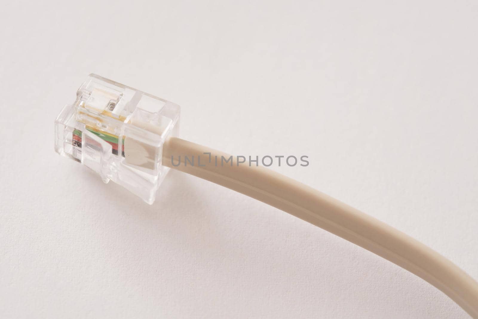 Clear plastic telephone plug or jack and cable over a white background with copy space in a communications concept