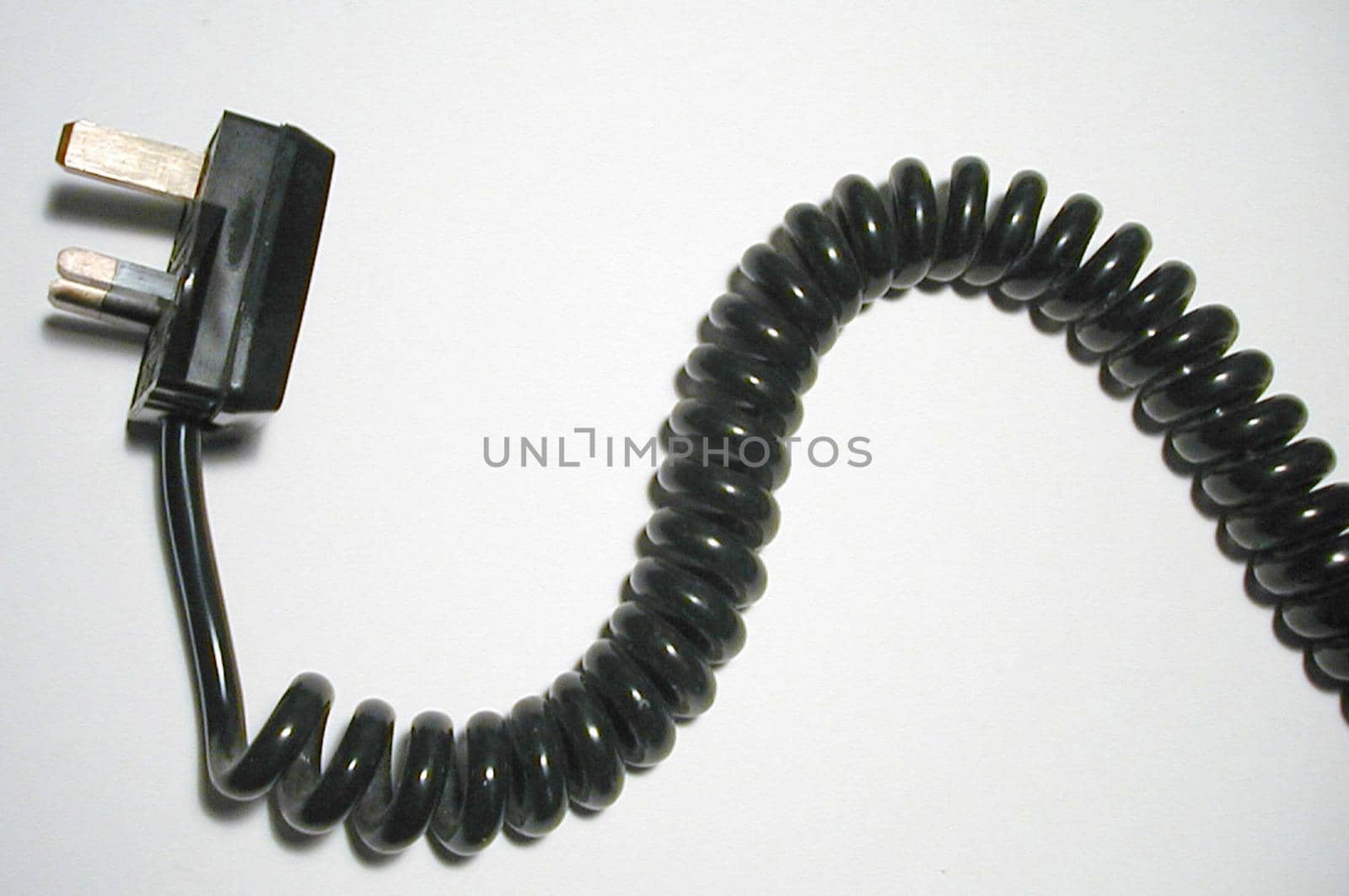 Spiral black cord with British plug displayed in a wavy line over white