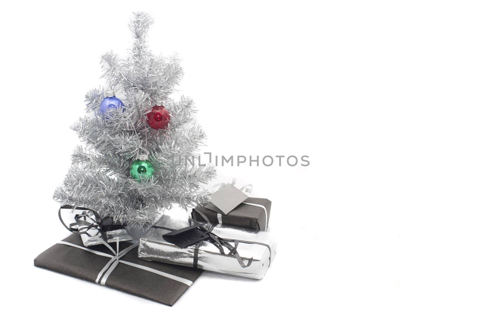 a small artificial silver tinsel christmas tree with presents inderneath