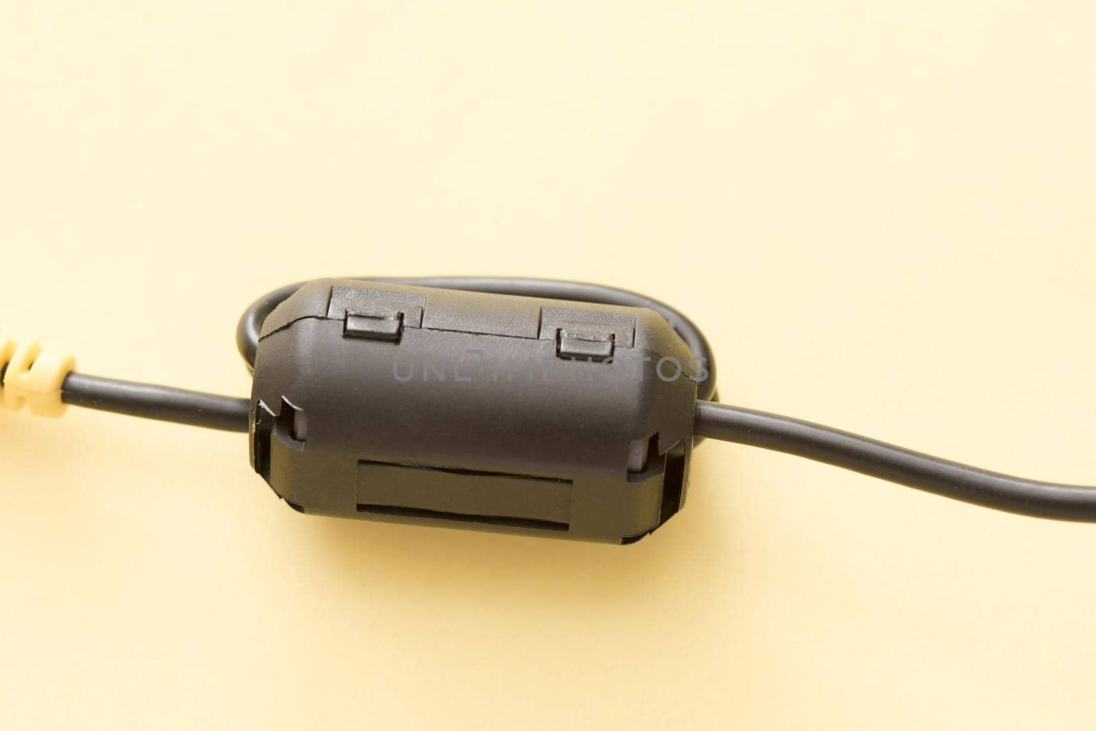 Close up of a black ferrite bead attached to a cable, isolated on a plain background.