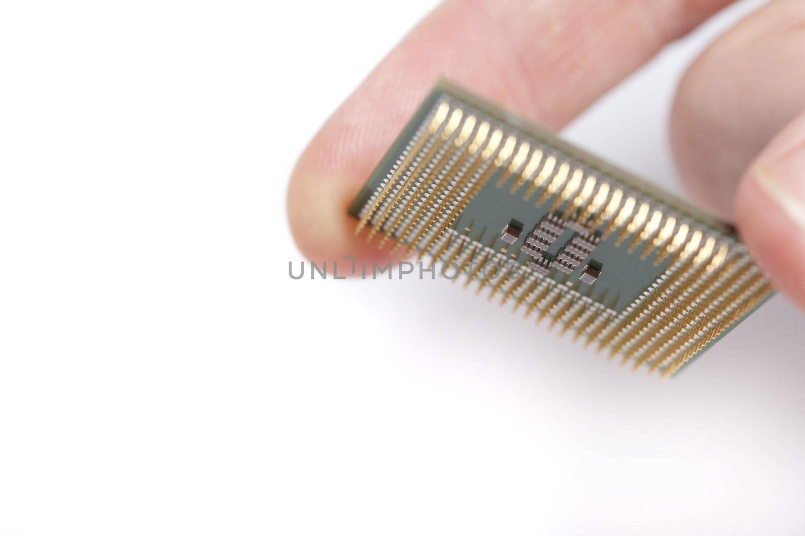 Close up macro view of a computer microprocessor held between the fingers of person over white with copy space