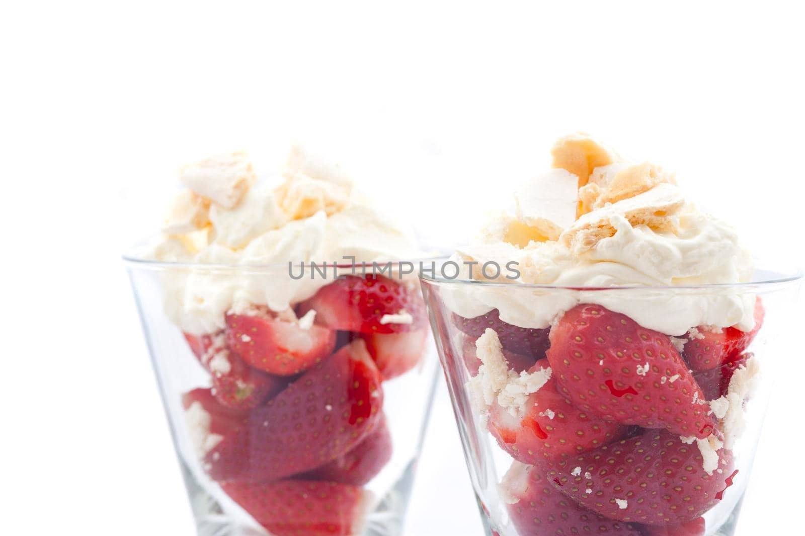Close up view of ripe red luscious strawberries served with whipped cream in tall glasses isolated on white