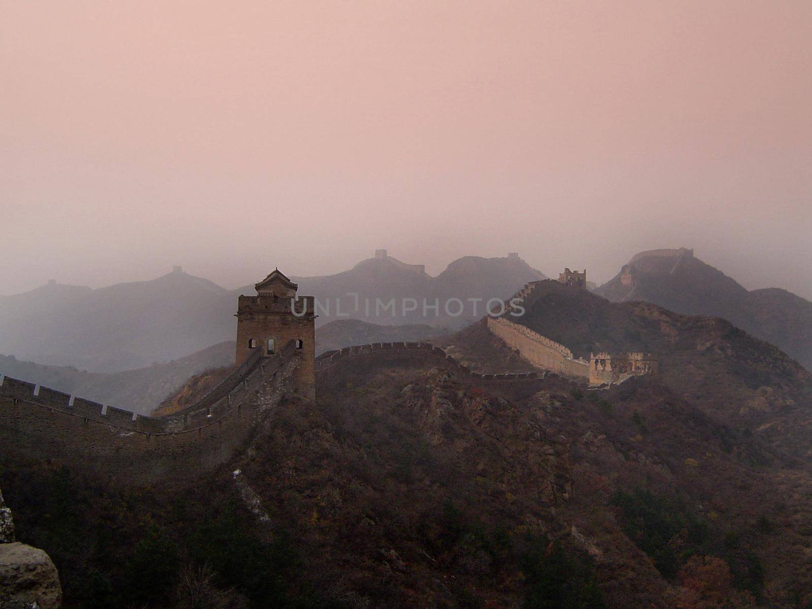 Atmospheric scenic landscape in colorful mist of the Great Wall of China and its lookout towers stretching away across mountain peaks in a travel concept