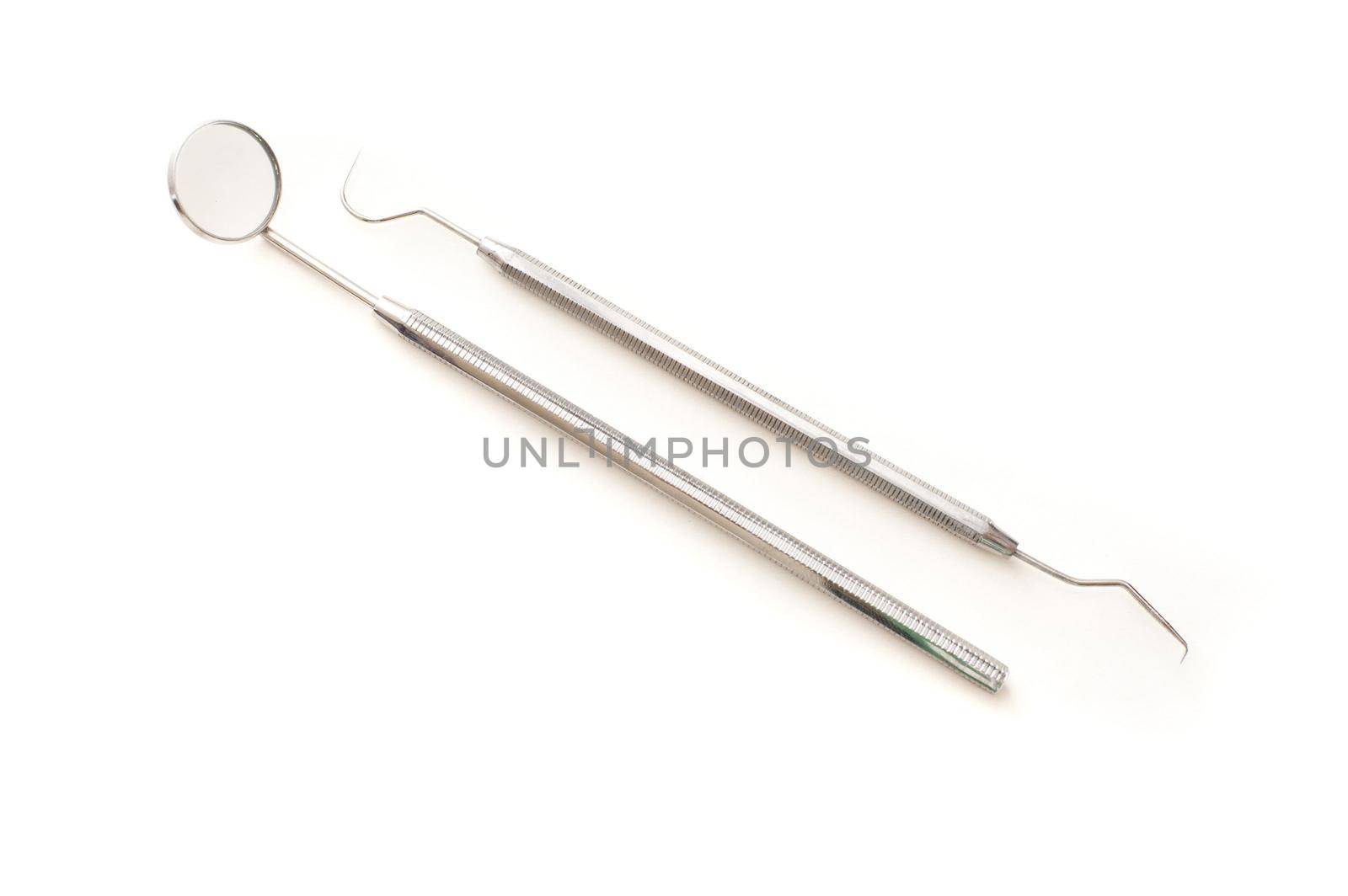 Dentists tools displayed on white with a stainless steel mirror and pick for examining teeth for caries and decay in his surgery, medical and healthcare concept