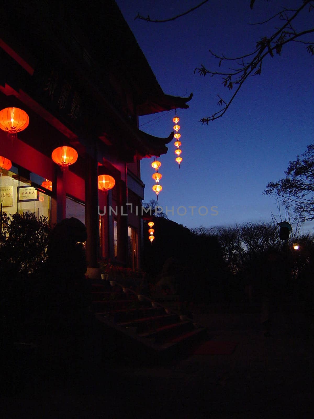 Door to a traditional Chinese house lit by red lanterns shining in the darkness of the night in a welcoming scene