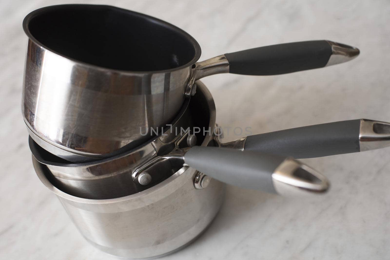 Stack of clean metal pans of assorted styles for cooking the food on a kitchen table