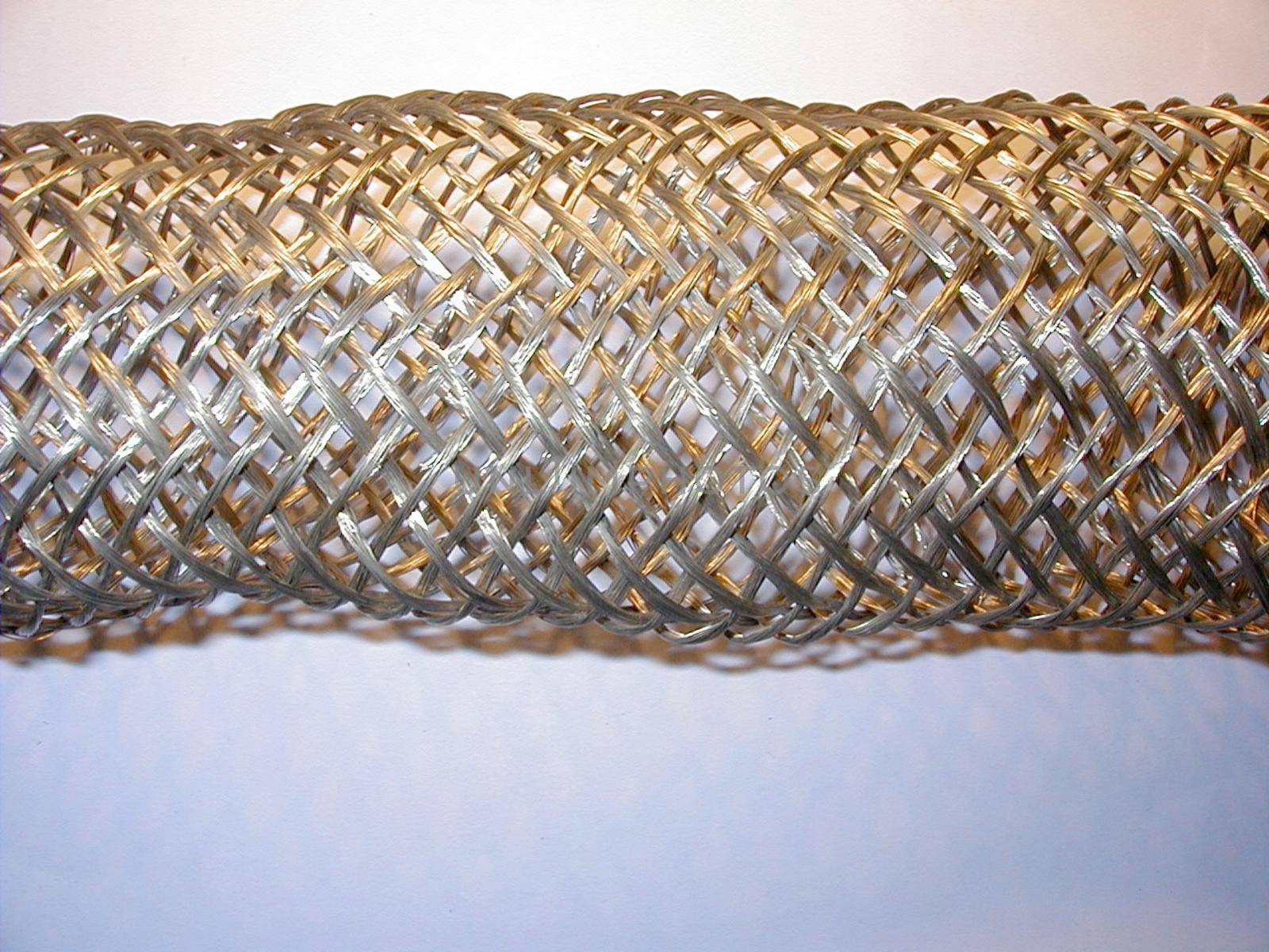 Cropped close up on flexible stainless steel metal tubing section over gray background