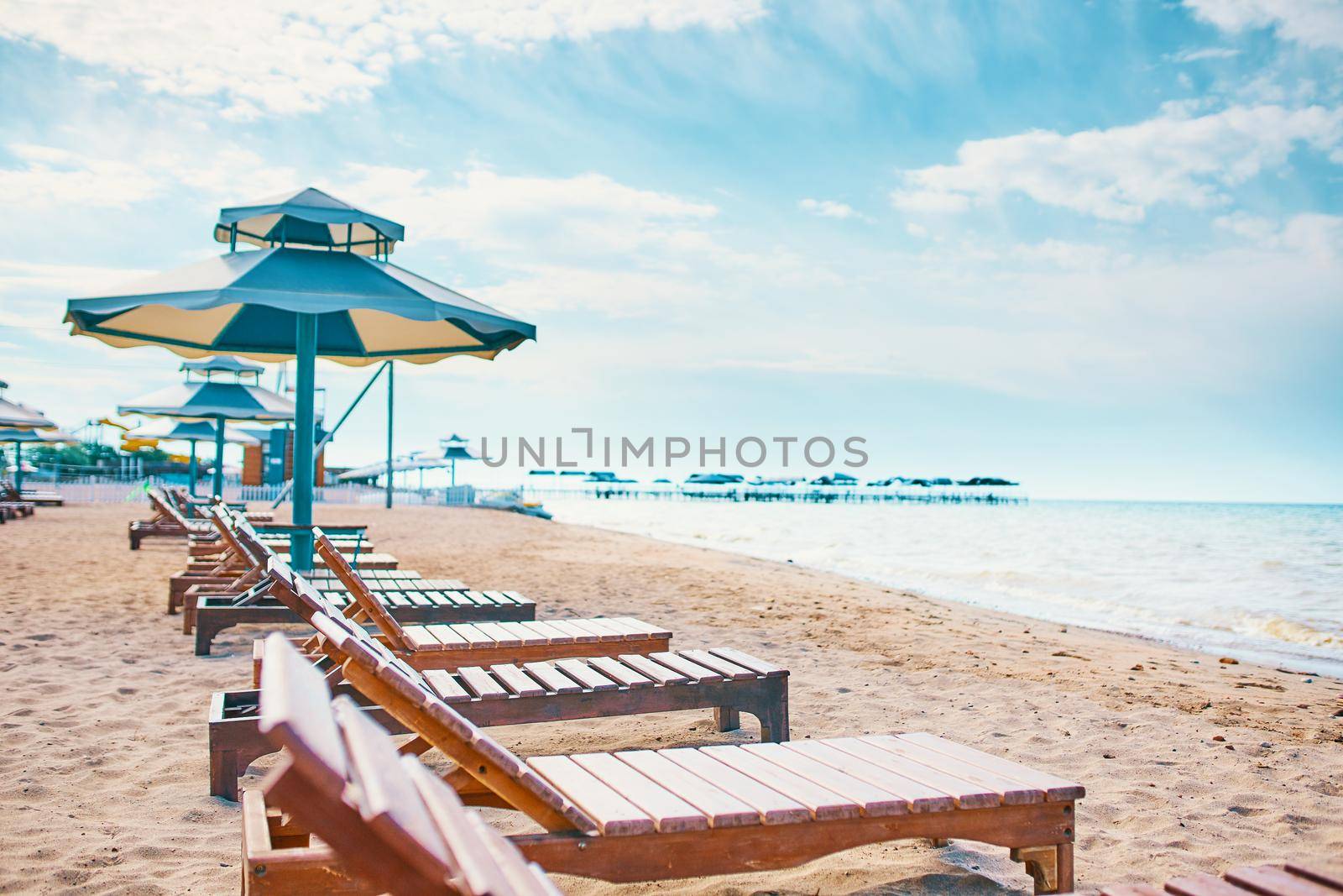 Sunbeds on the beach. A row of sun umbrellas with seats on the lake shore.