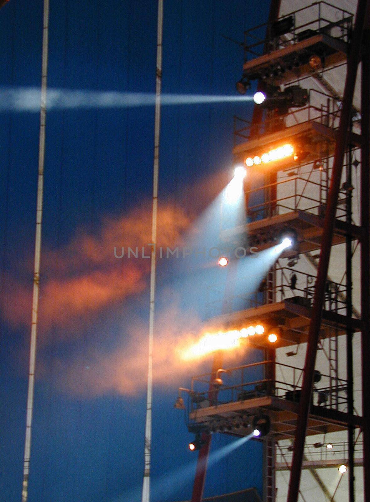 Tower supporting spotlights at a circus show arranged on various levels in assorted colors beaming down at night
