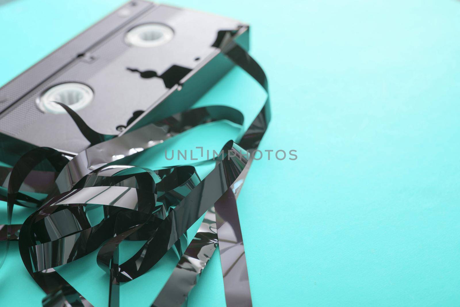 Broken VHS video tape on plain cyan background with copy space