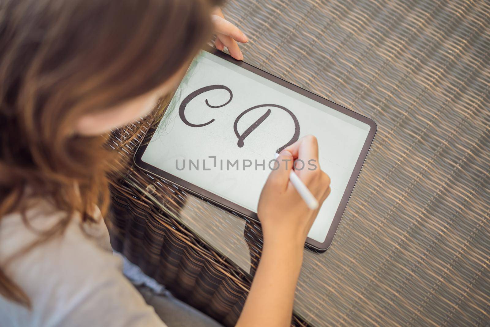 Calligrapher Young Woman writes phrase on digital tablet. Inscribing ornamental decorated letters. Calligraphy, graphic design, lettering, handwriting, creation by galitskaya