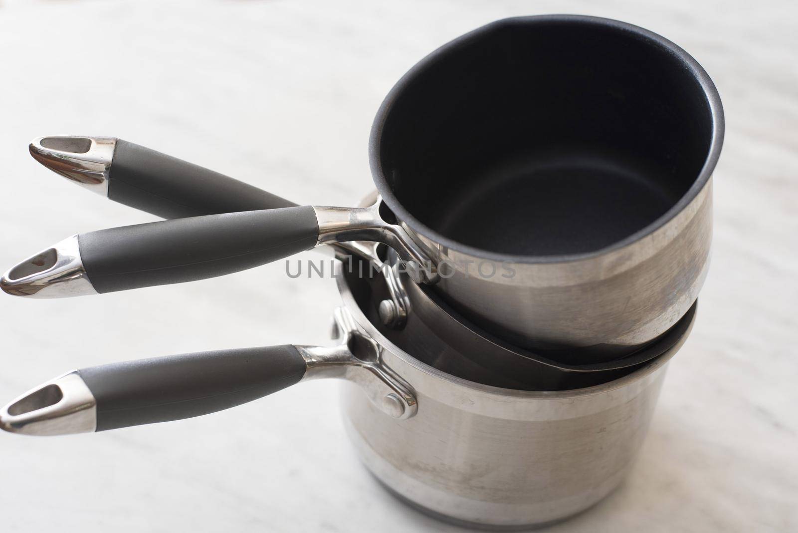 Three clean empty stainless steel pots with non-stick interiors stacked on top of each other