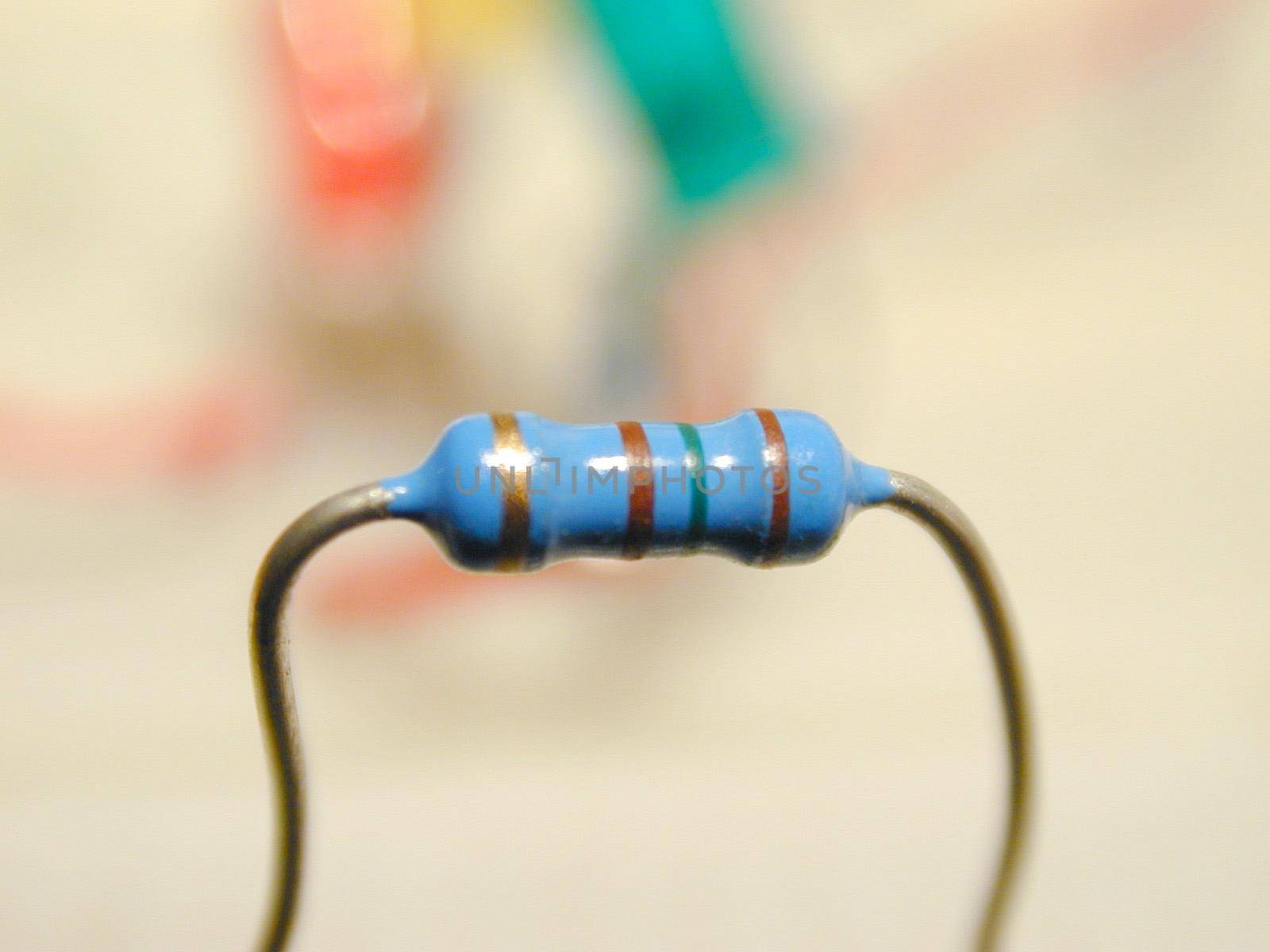 Close up of a blue electronic resistor, isolated on a blurred background.
