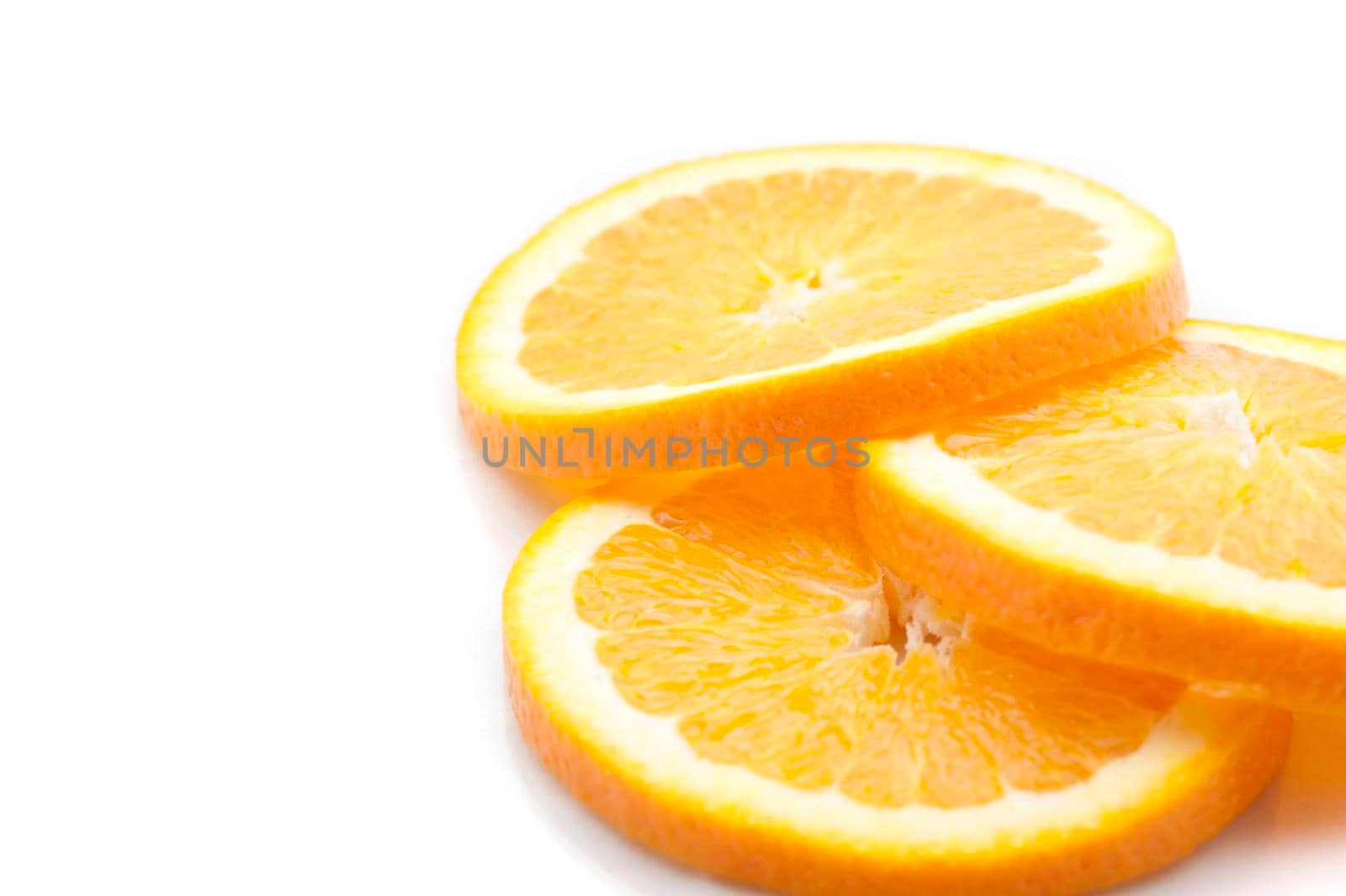 Closeup view of three slices of thinly sliced fresh orange showing the segmented pulp and rind ready for use as a garnish lying on a white background with copyspace