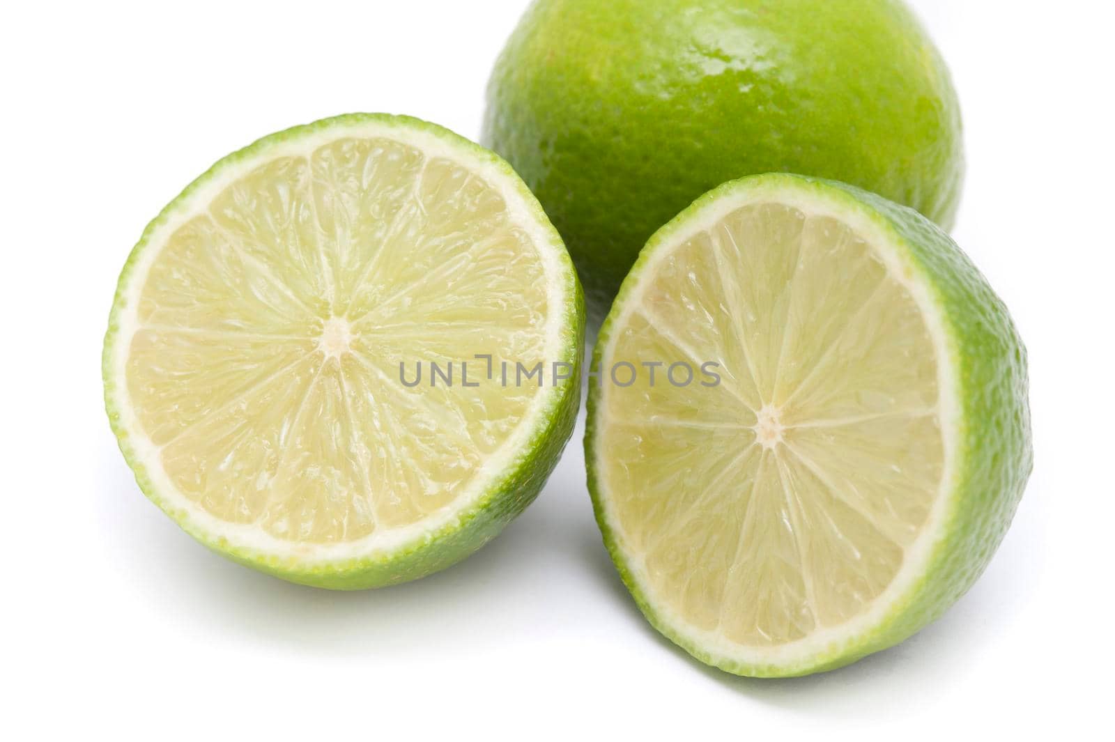Close up of halved and whole fresh organic limes showing the juicy acidic pulp used as a flavouring in cooking