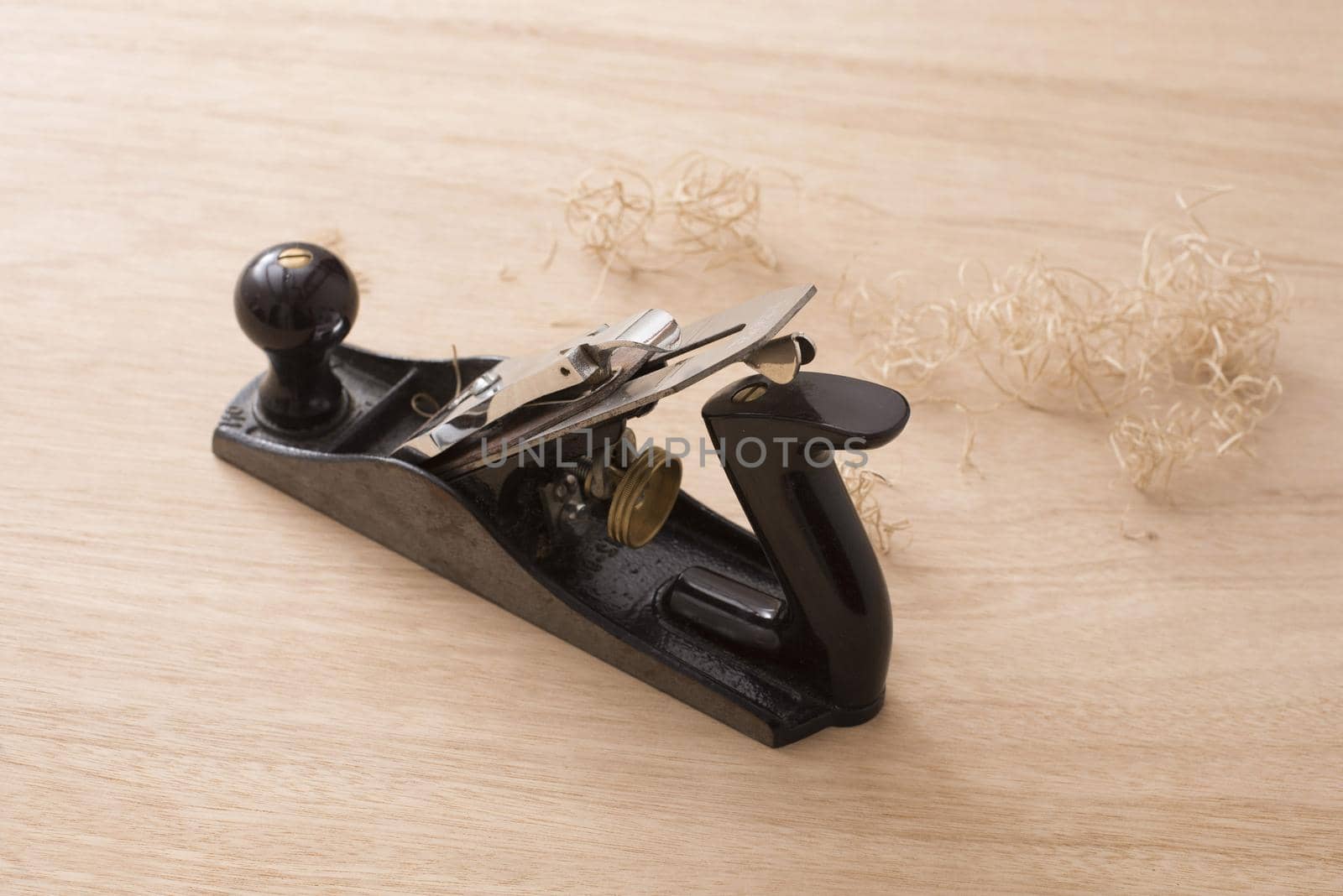 Carpenters plane tool and shavings on wooden surface viewed from high angle