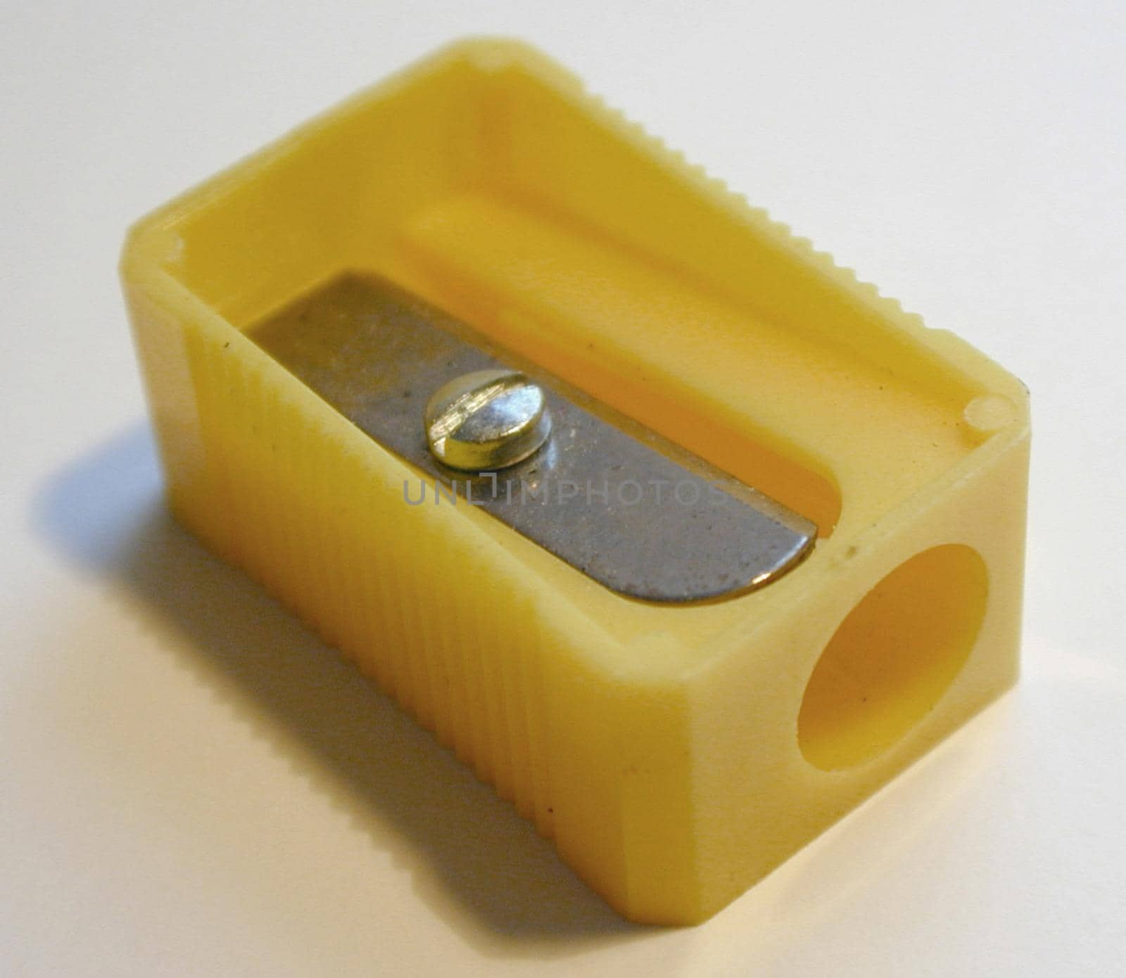 Simple yellow plastic pencil sharpener with a close up view on the blade at the top for school or office supplies