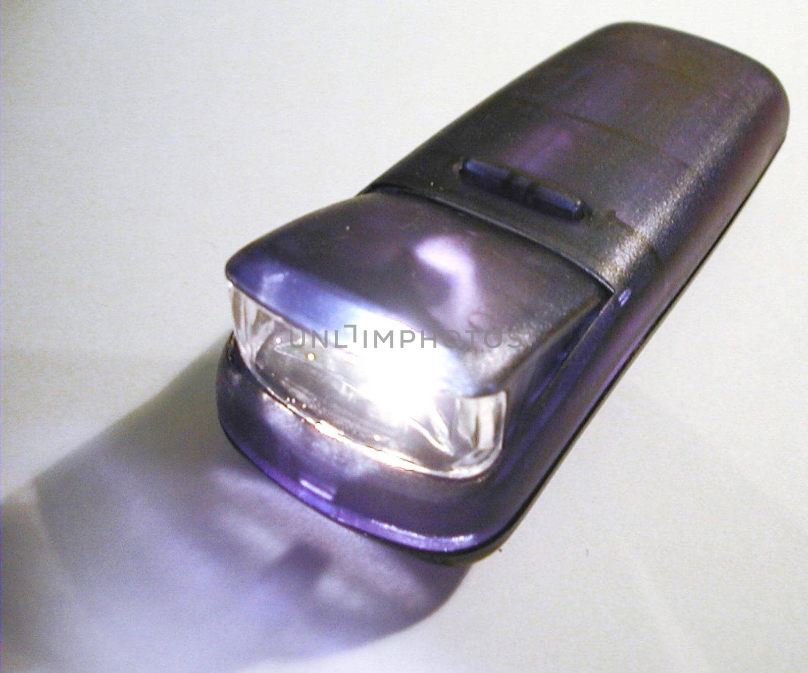 Close Up of Illuminated Purple Flashlight Torch with Lit Lamp on White Background
