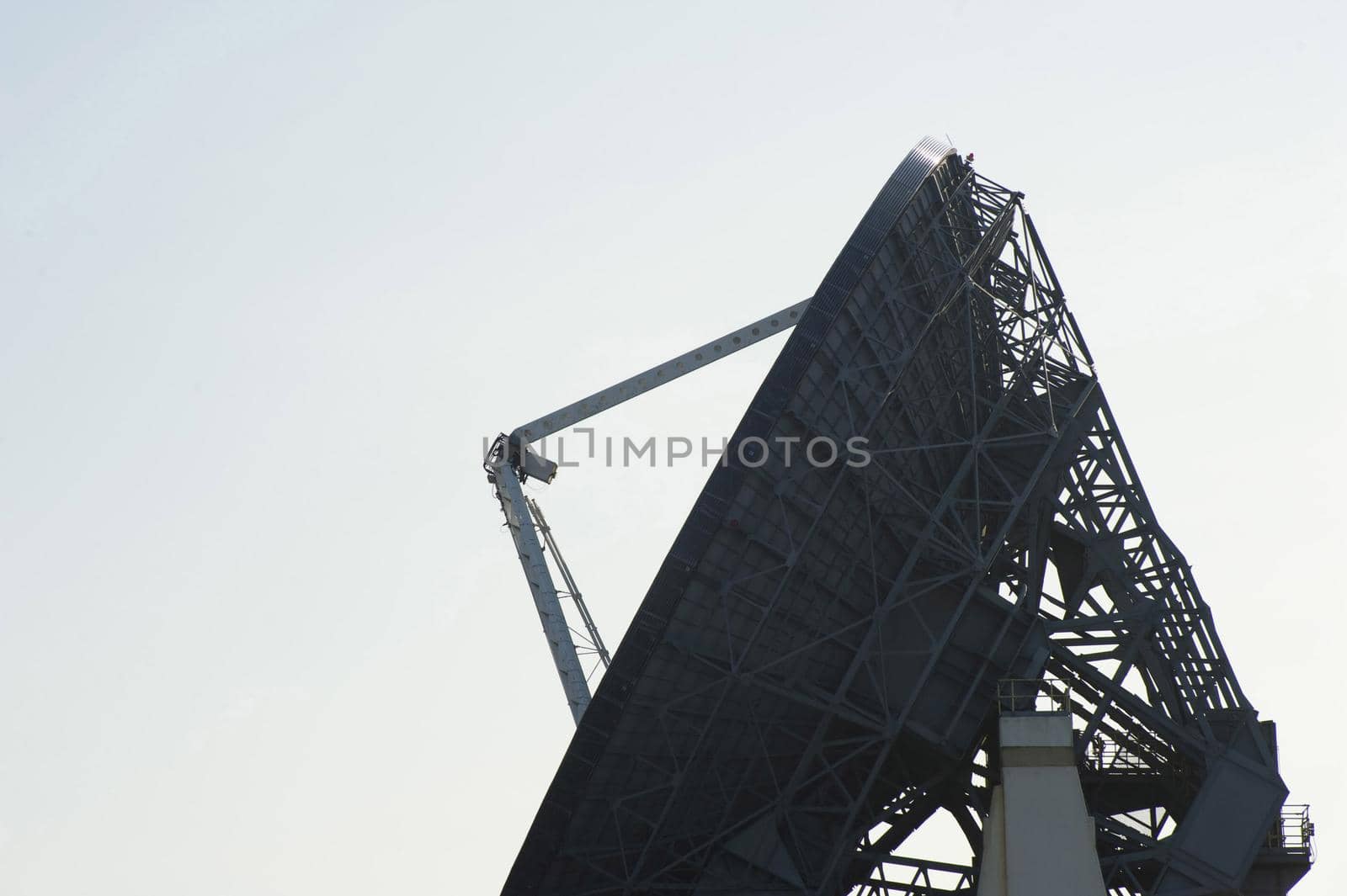 Silhouette of a parabolic dish satellite antenna in side view over a grey sky with copy space in a communications concept