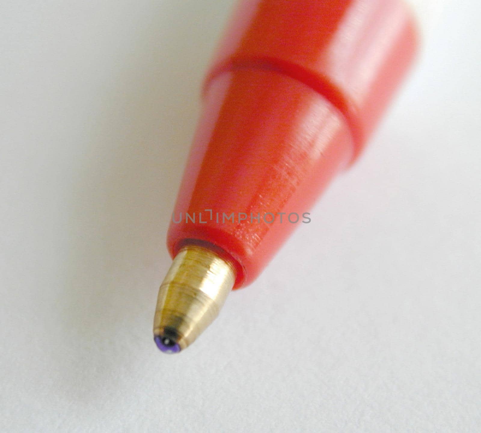 Extreme close up of roller ball pen tip with metal end and a red colored body