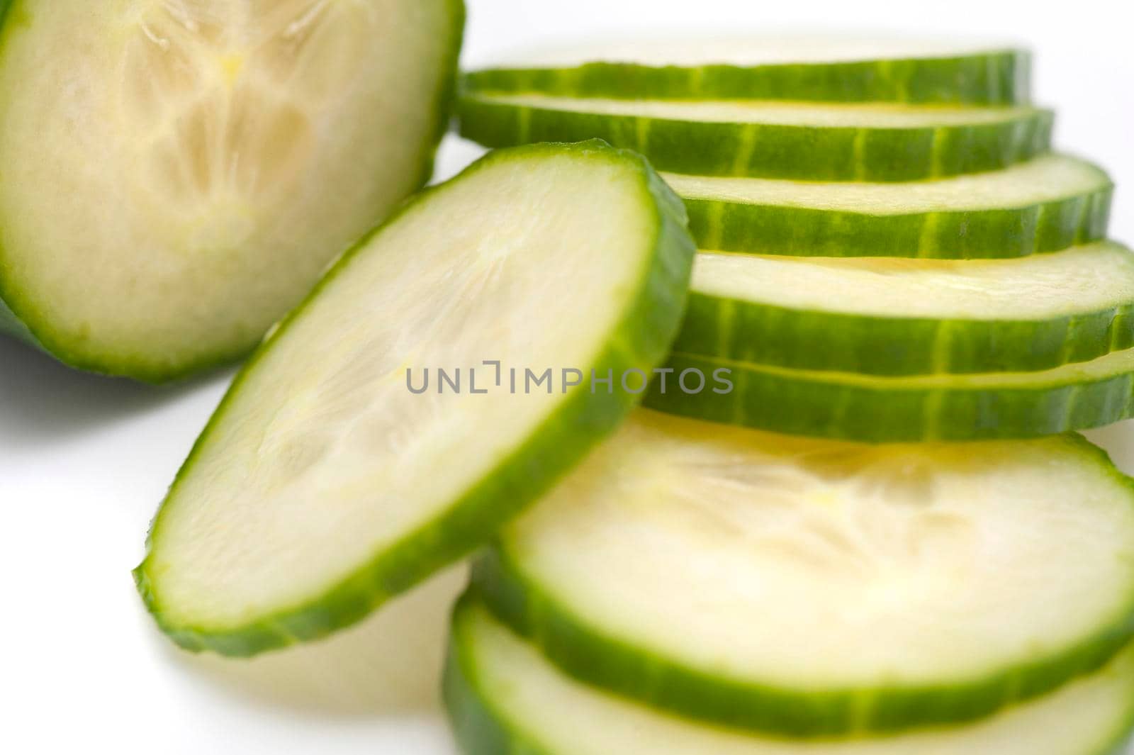 Closeup view of succulent thinly sliced cucumber being prepared as a salad ingredient or for healthy vegetarian cuisine
