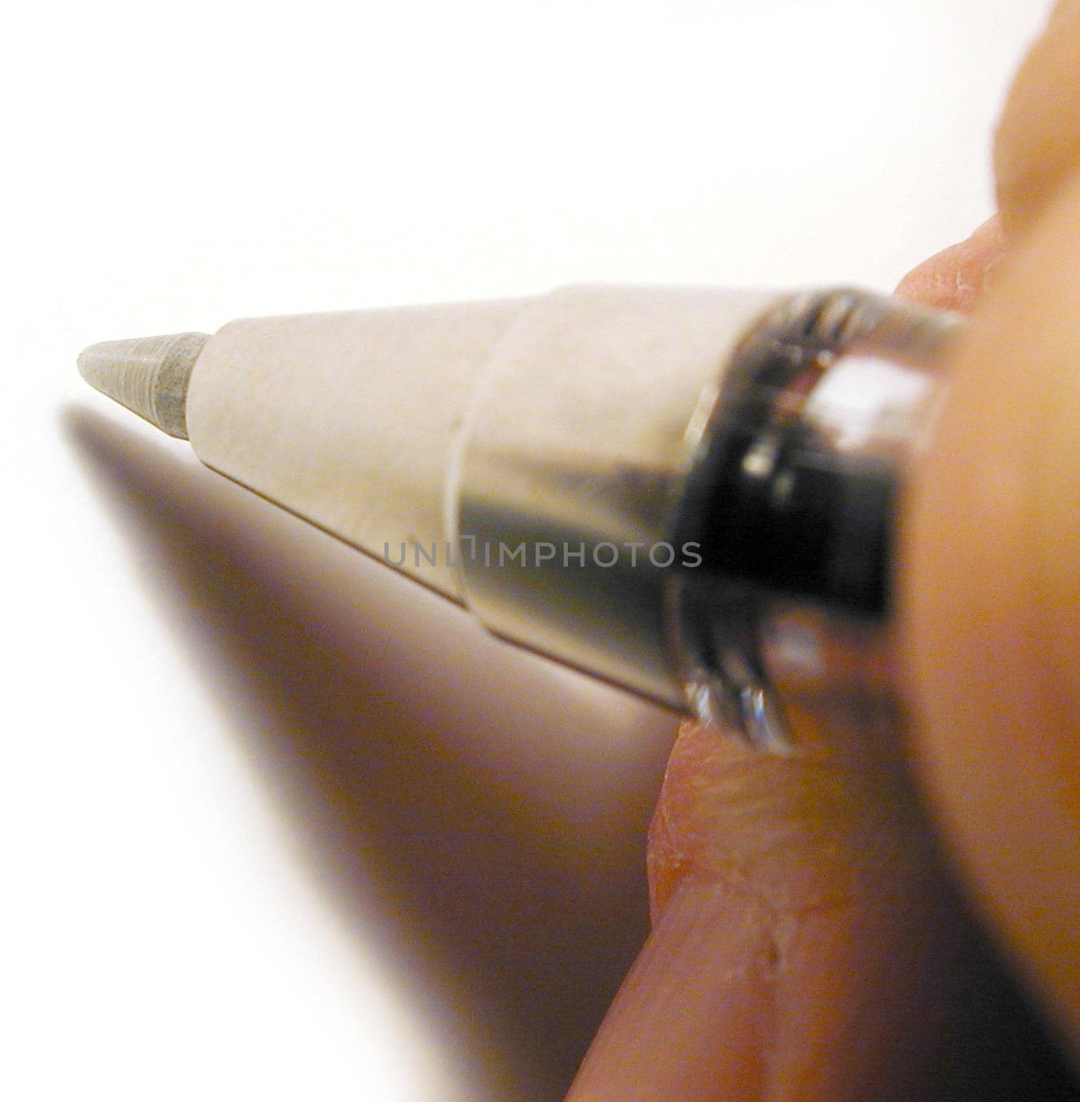 Extreme close up on fingers holding ball point pen over blank white paper as if to write something