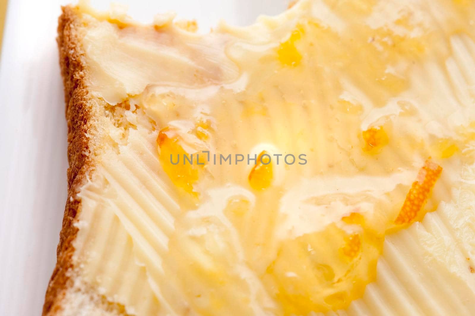 Slice of breakfast toast spread with butter and topped with marmalade or preserve