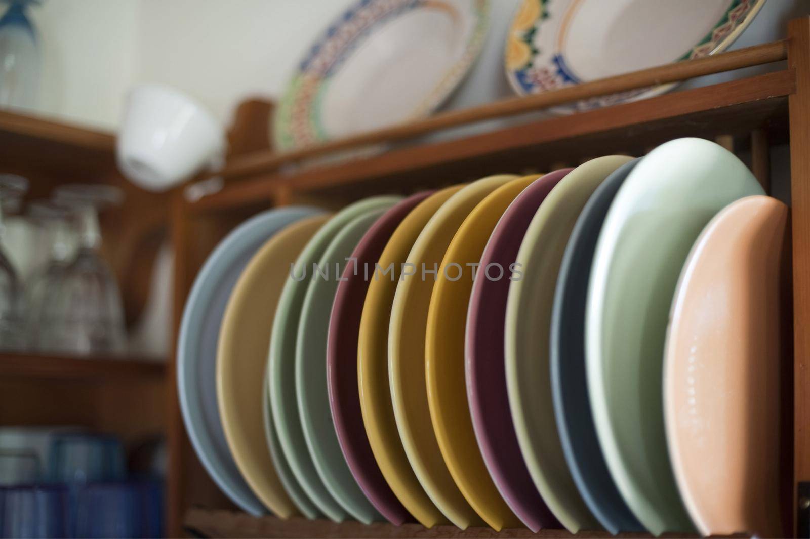 Assorted colorful plates in a wooden wall mounted rack in a kitchen viewed close up in a food and catering concept