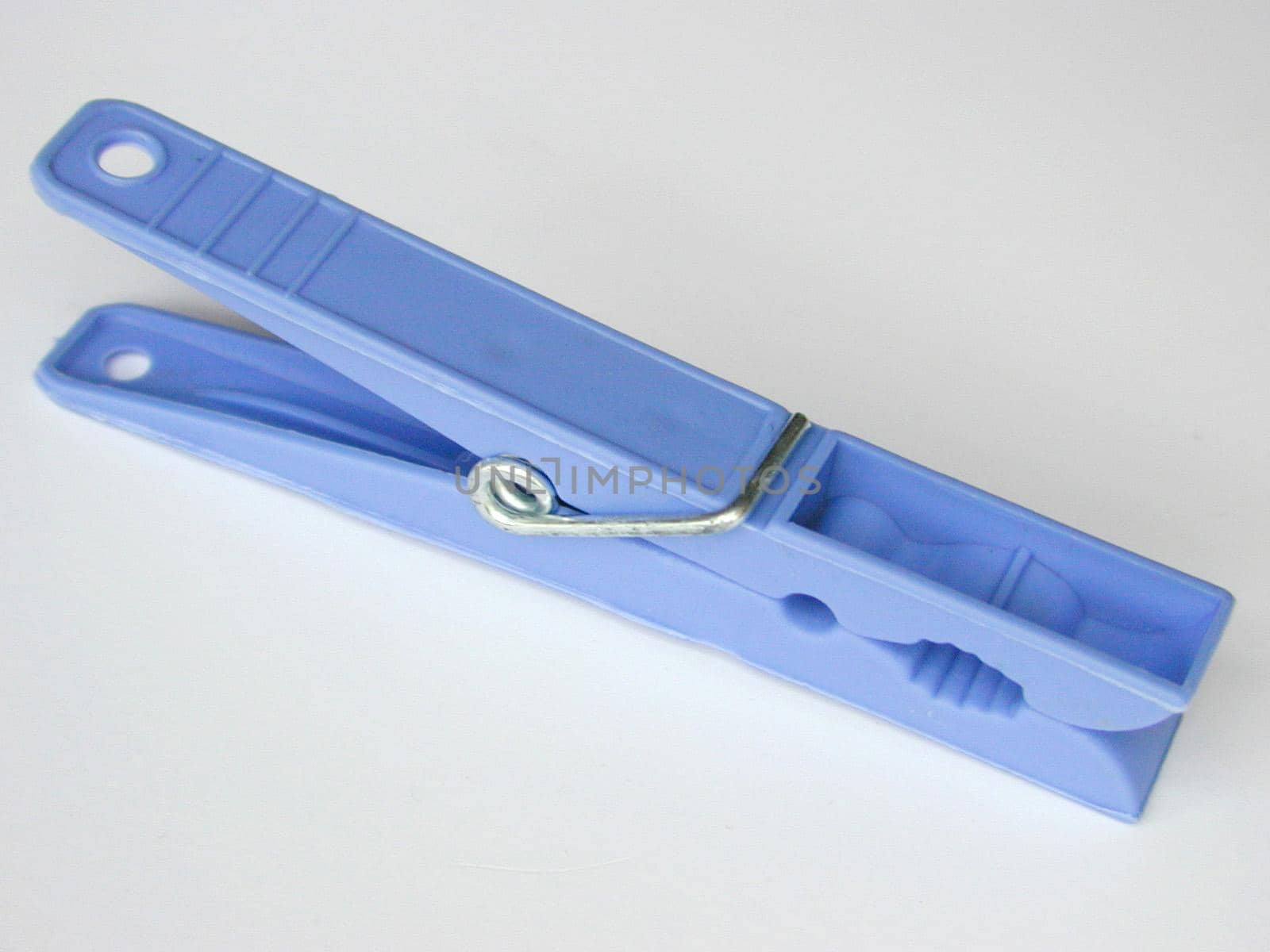 Spring-type blue plastic clothespin, symbol of household and laundry, close-up on gray