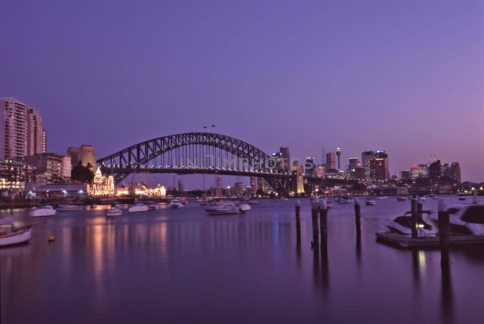 Purple sunset over Sydney Harbour Bridge, Australia on a tranquil summer evening with boat traffic and city lights in a transport and travel concept