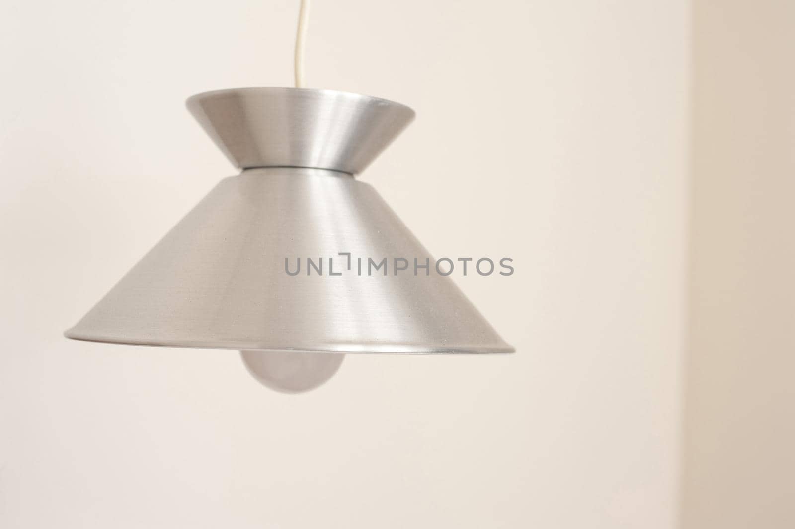 Stylish simple metal light fitting hanging from the ceiling with a shiny silver metallic finish shade and globe - switched off