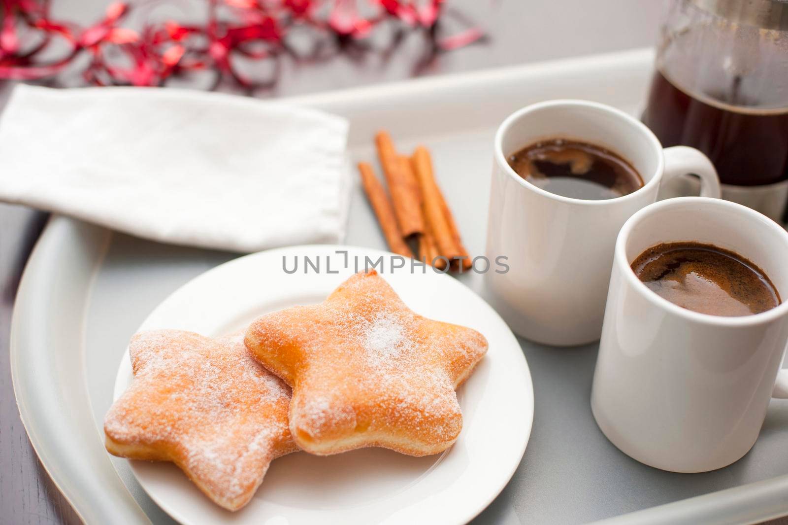 Serving of espresso coffee and freshly baked sugared Christmas doughnuts in the shape of a star for a festive Xmas coffee break