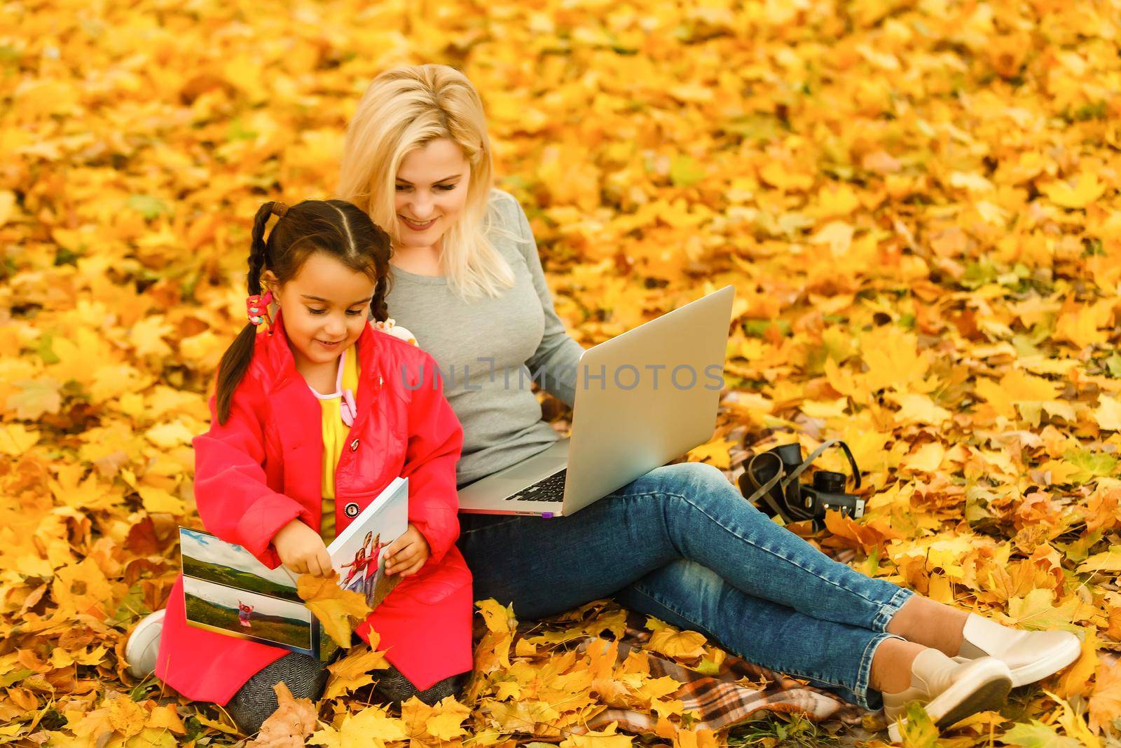 Urban woman and daughter with laptop in park. slim hipster woman in jeans using notebook. freelancer using communication technology remote work and eco-friendly lifestyle. by Andelov13