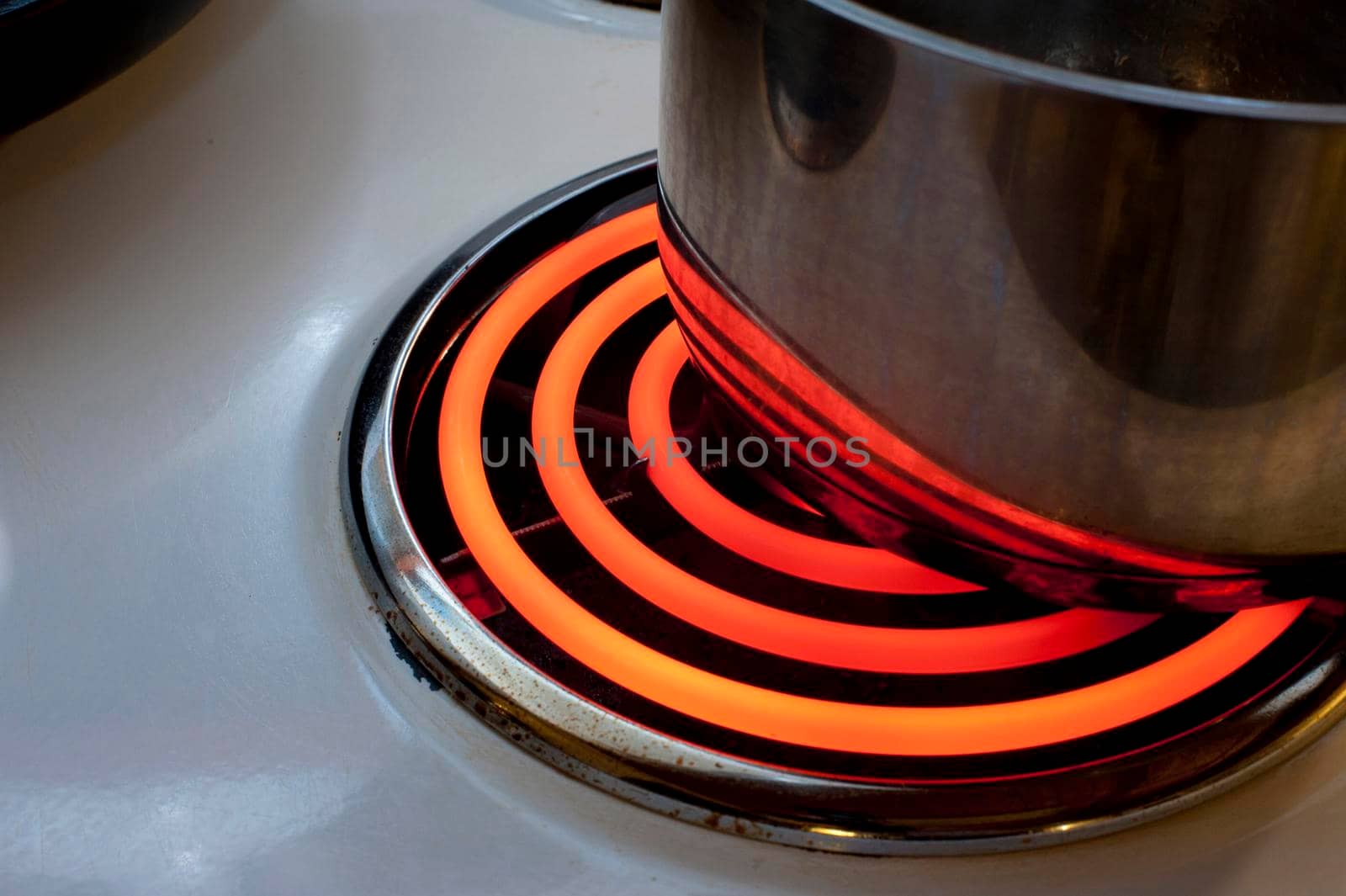 Cooking on the red hot spiral hotplate of an electric stove with a metal pot or saucepan