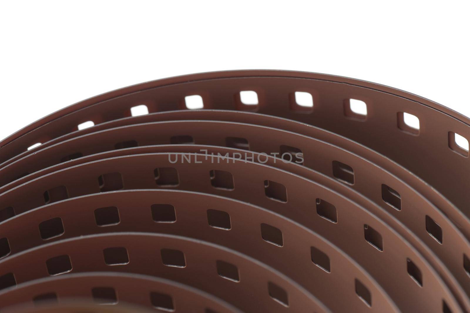 Close up detail of a roll of 35mm film viewed from a high angle showing the coils of the reel and sprockets , isolated on white