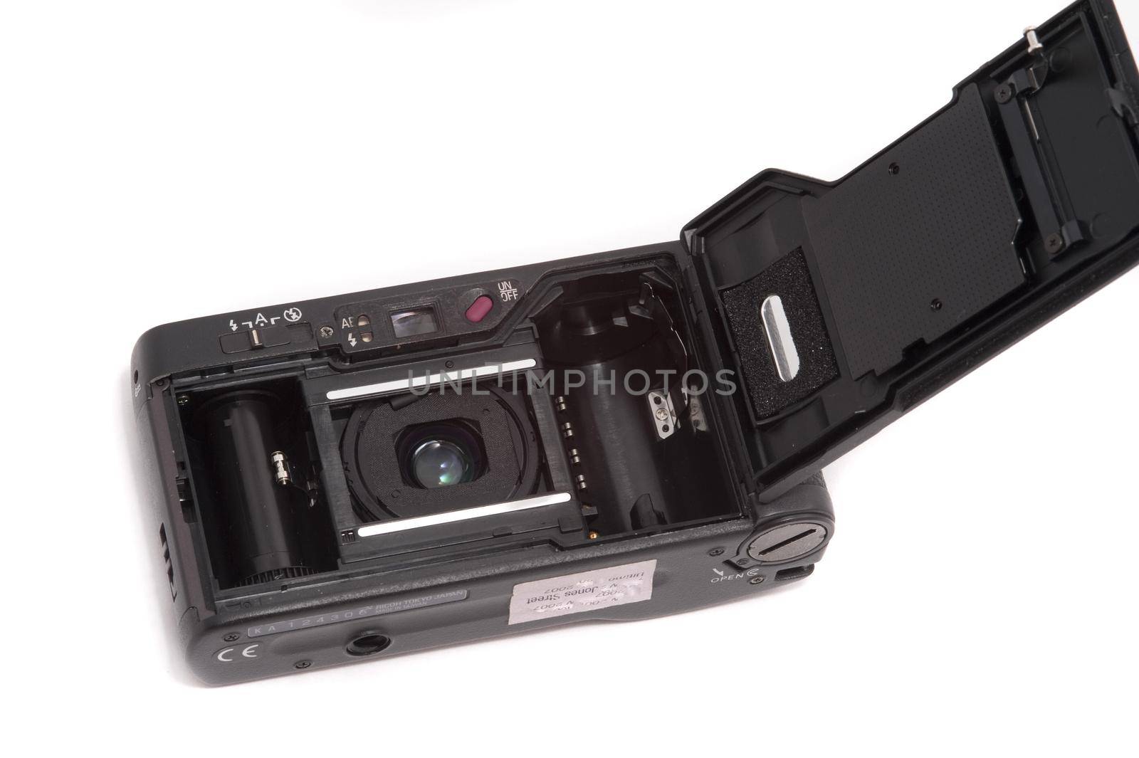 View of portable compact pocket camera face down over white background with open back