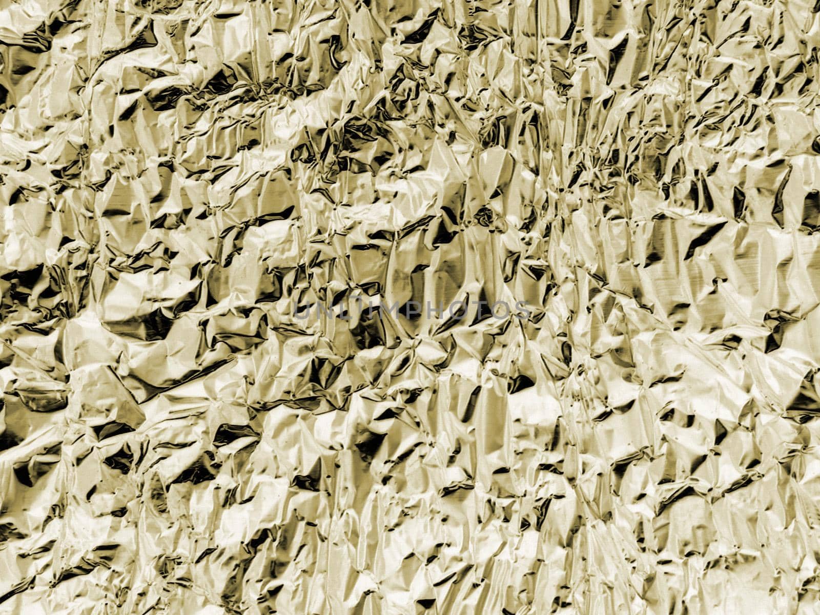 Detailed background of wrinkled foil in yellow hue with rough texture with copy space