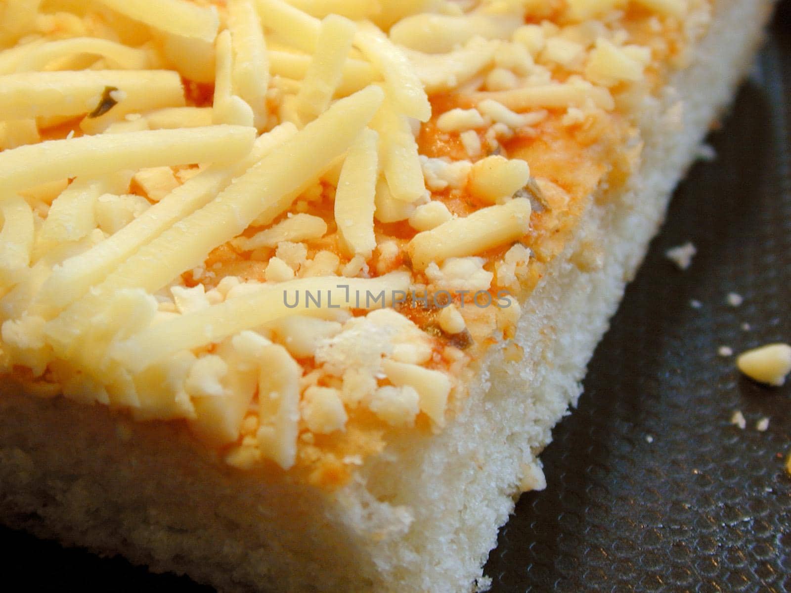 Slice of uncooked Italian pizza with a thick pastry base topped with tomato paste and grated cheese