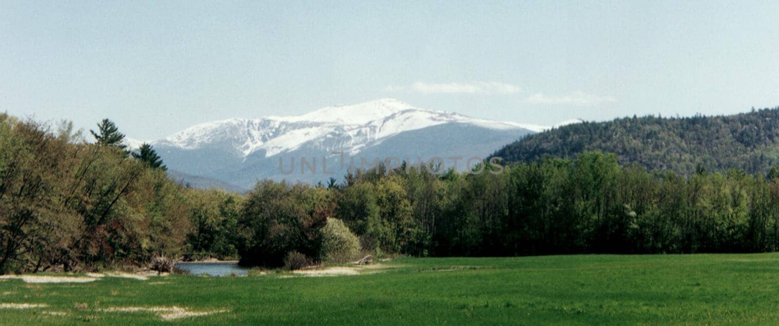 Snow-capped mountain panoramic landscape with forests and a small tranquil lake in the foreground, beauty in nature