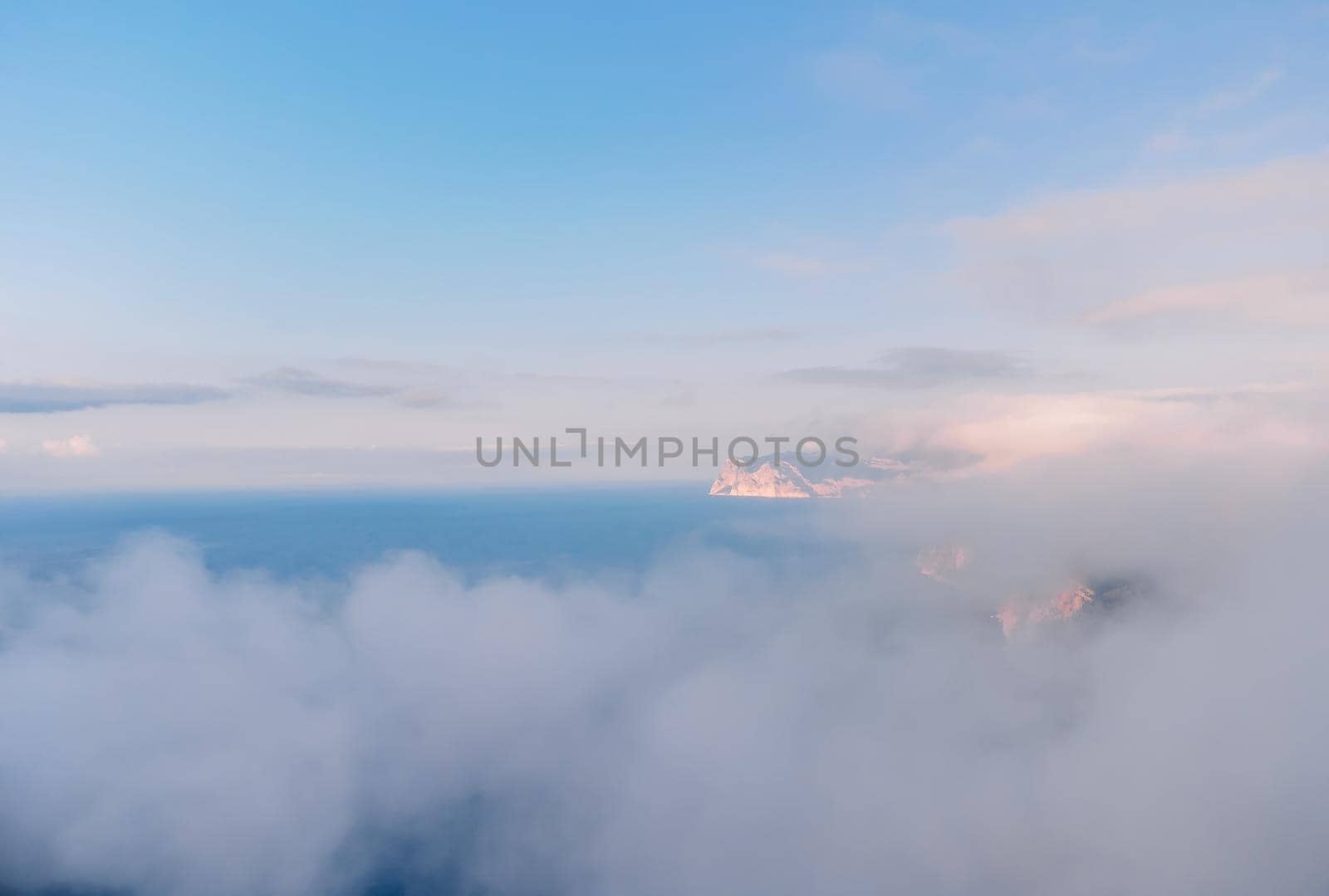 Aerial view. The drone flies over foggy and fluffy clouds. Blue sky sun and sea fog. Abstract aerial nature summer ocean sunset sea and sky background. Vacation, travel and holiday concept by panophotograph