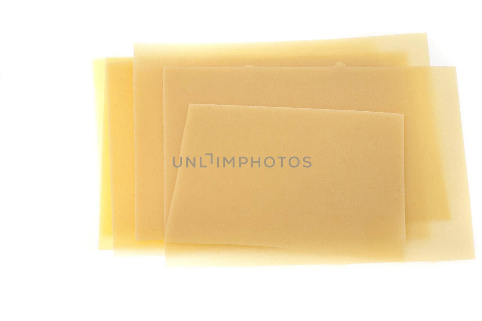 Dried sheets of uncooked Italian lasagne pasta made from durum wheat on a white background