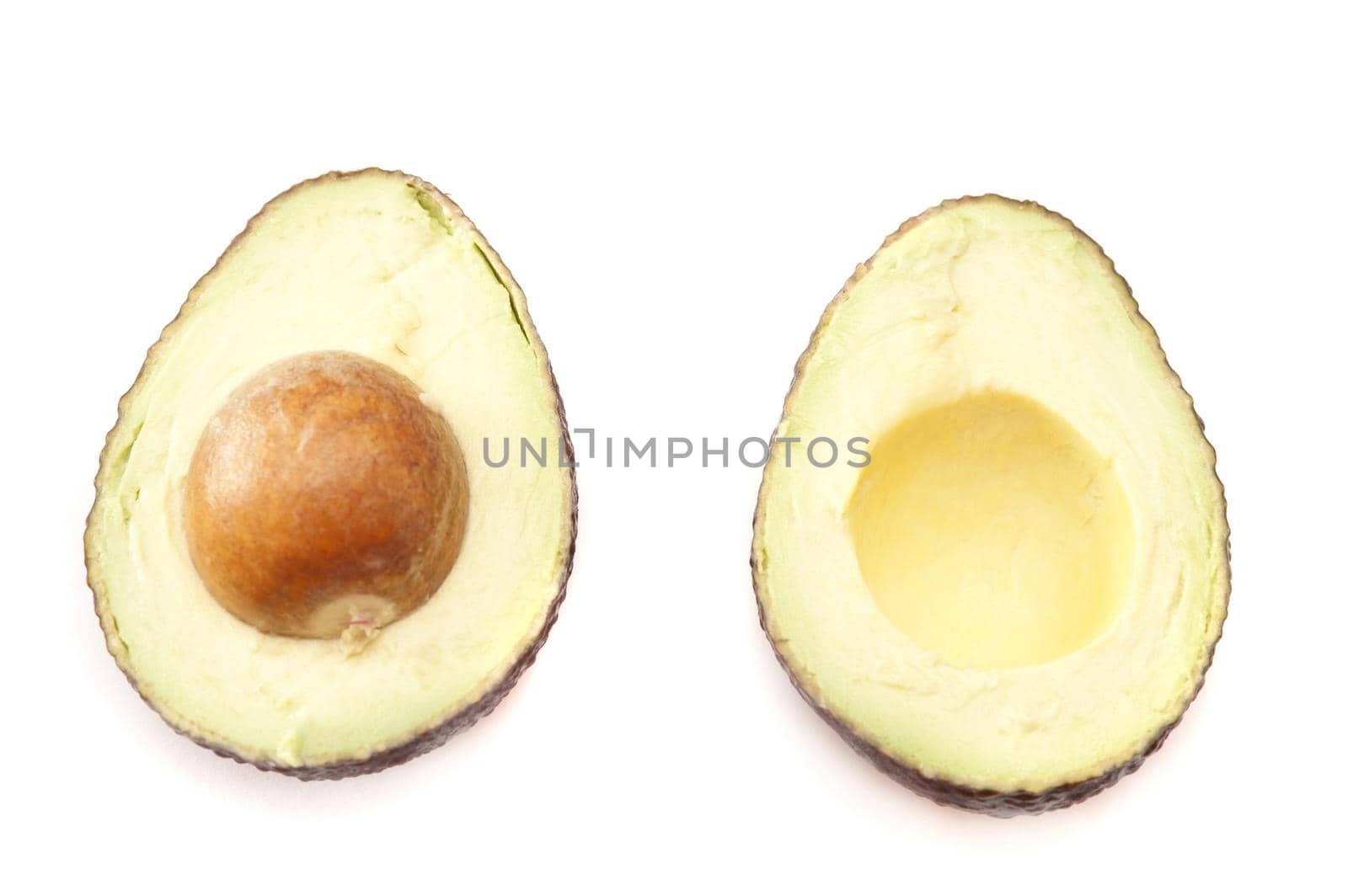 Halved fresh tropical avocado pear viewed from above with the pip still in for a delicious healthy nutrient rich salad ingredient, isolated on white