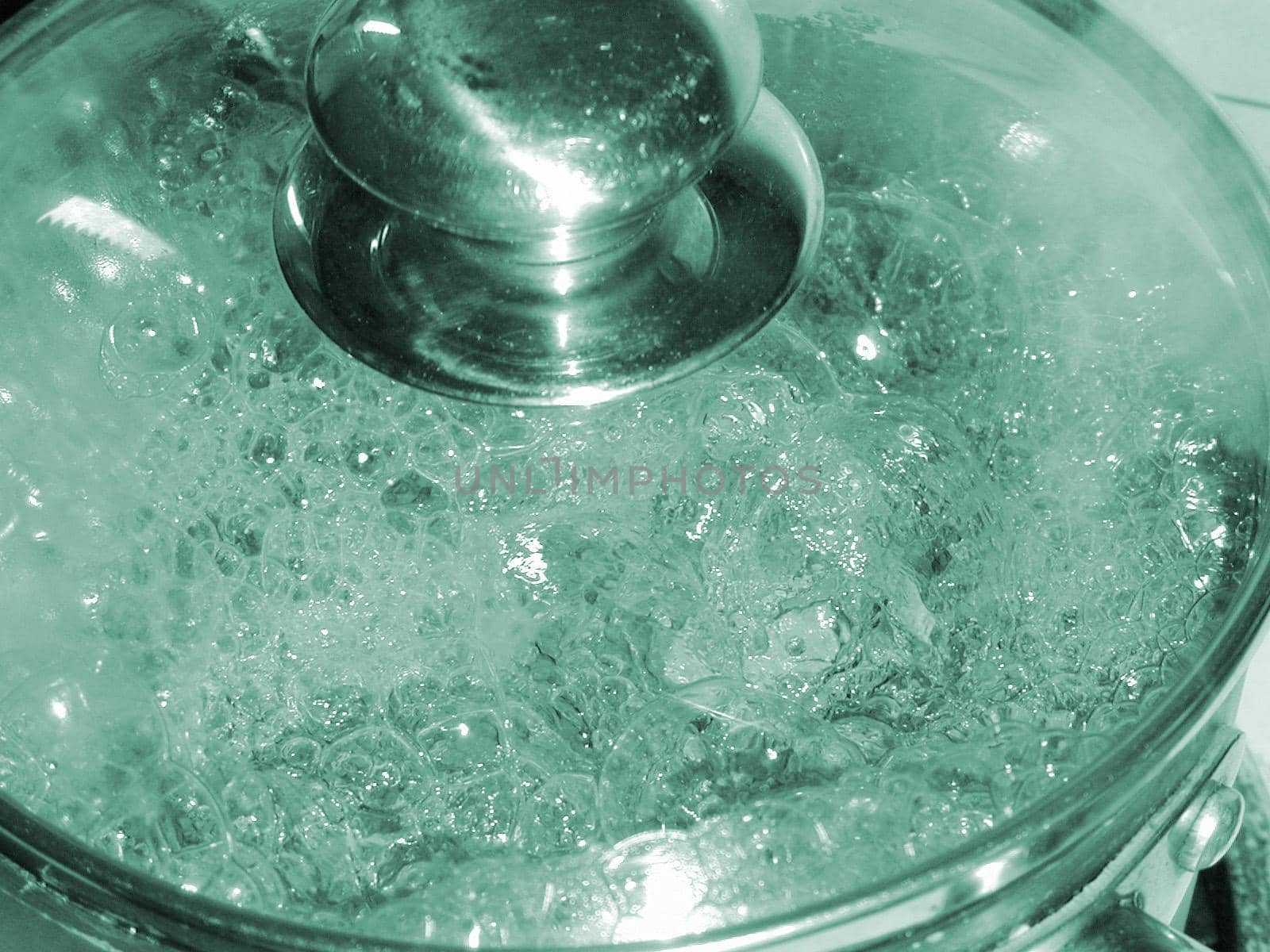 Boiling pot of water on a stove with a glass lid so that the bubbles are visible