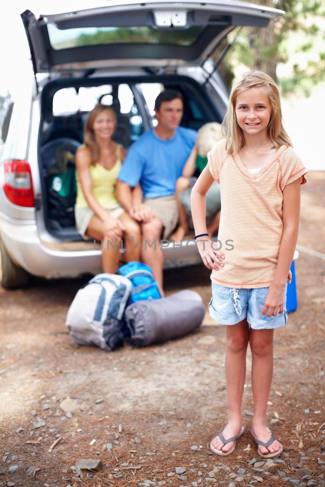Young girl smiling. Full length of young girl smiling with family sitting in a car